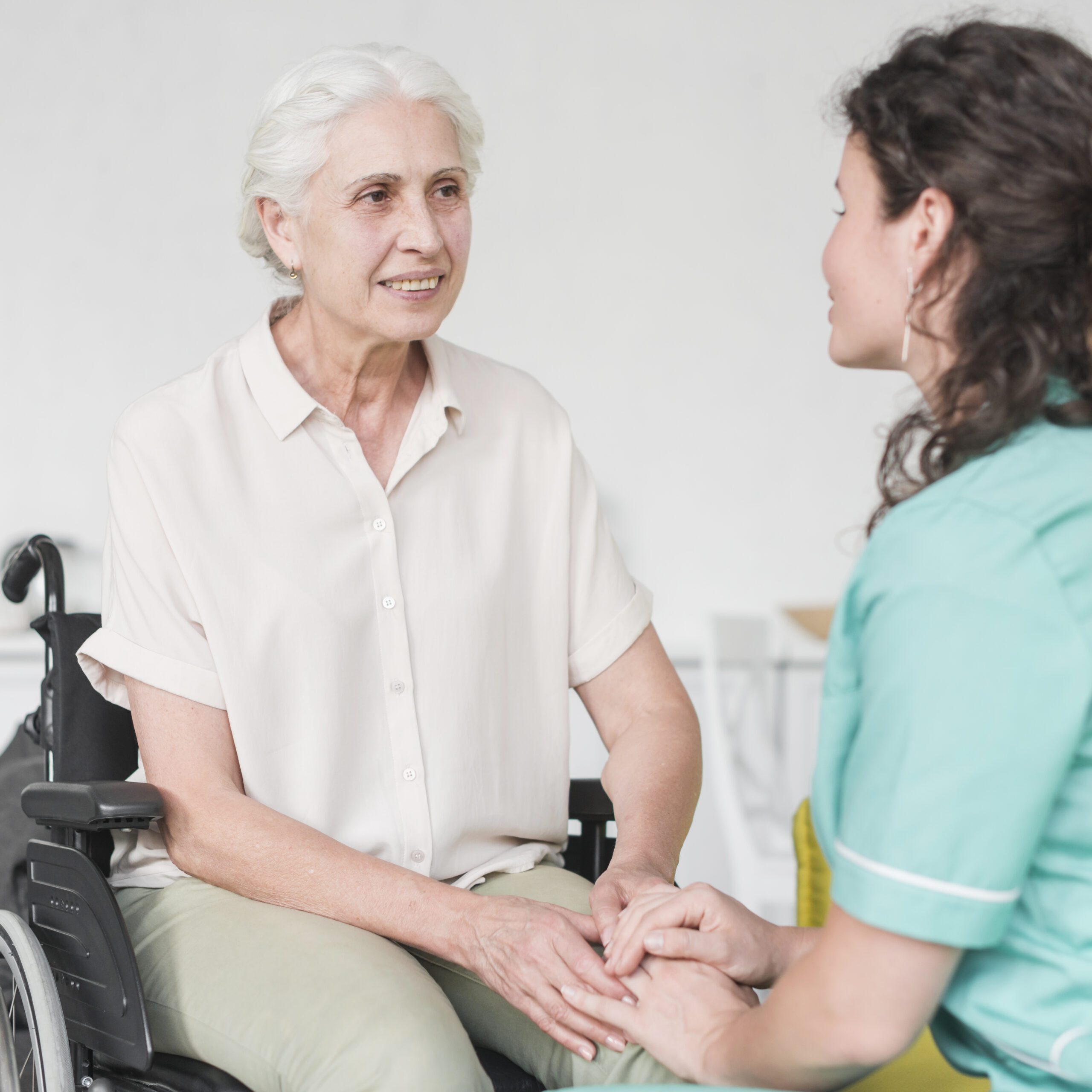 Happy disabled nurse sitting on wheel chair looking at caretaker